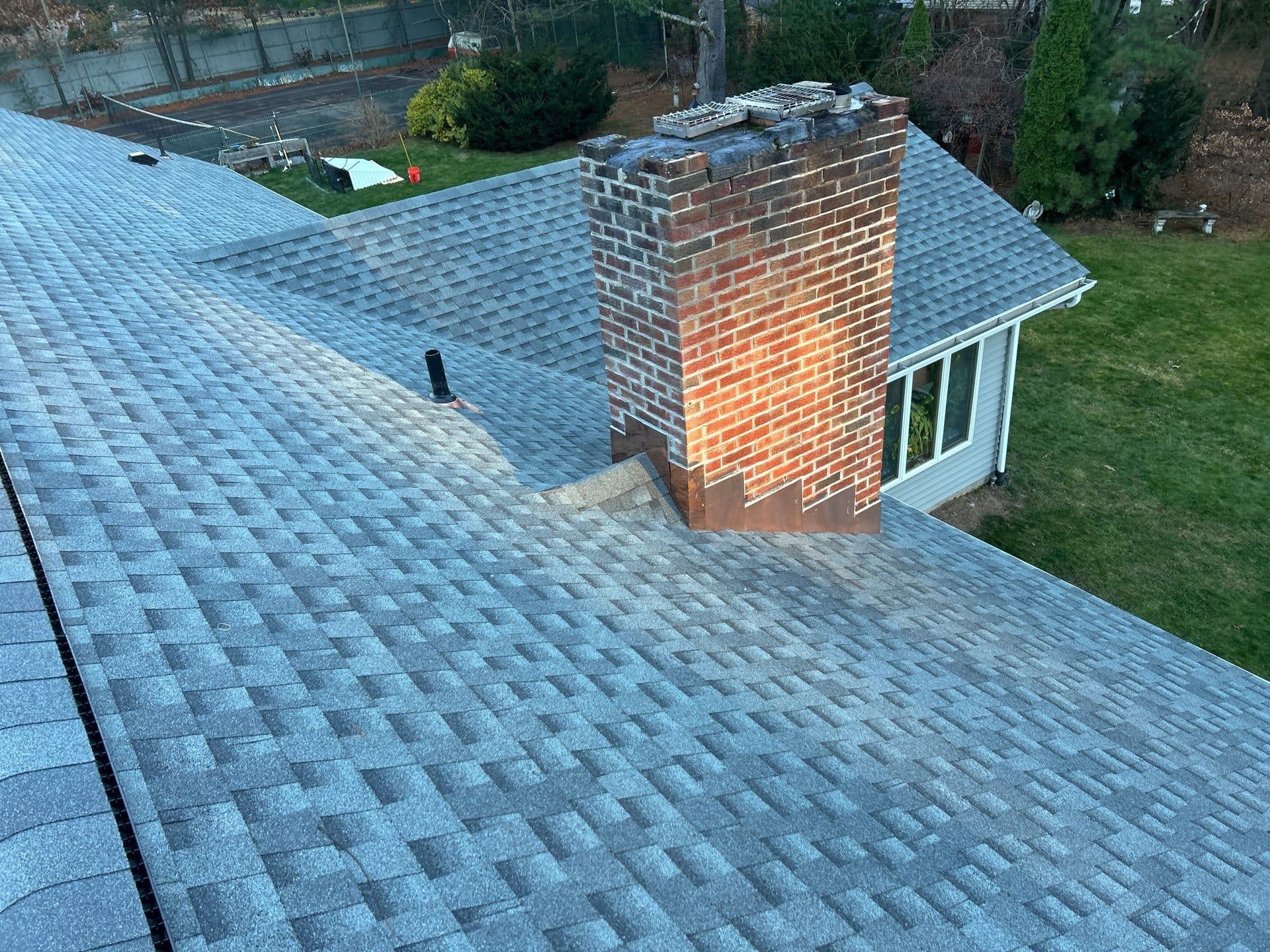 New shingles and flashing installed across a residential roof surface