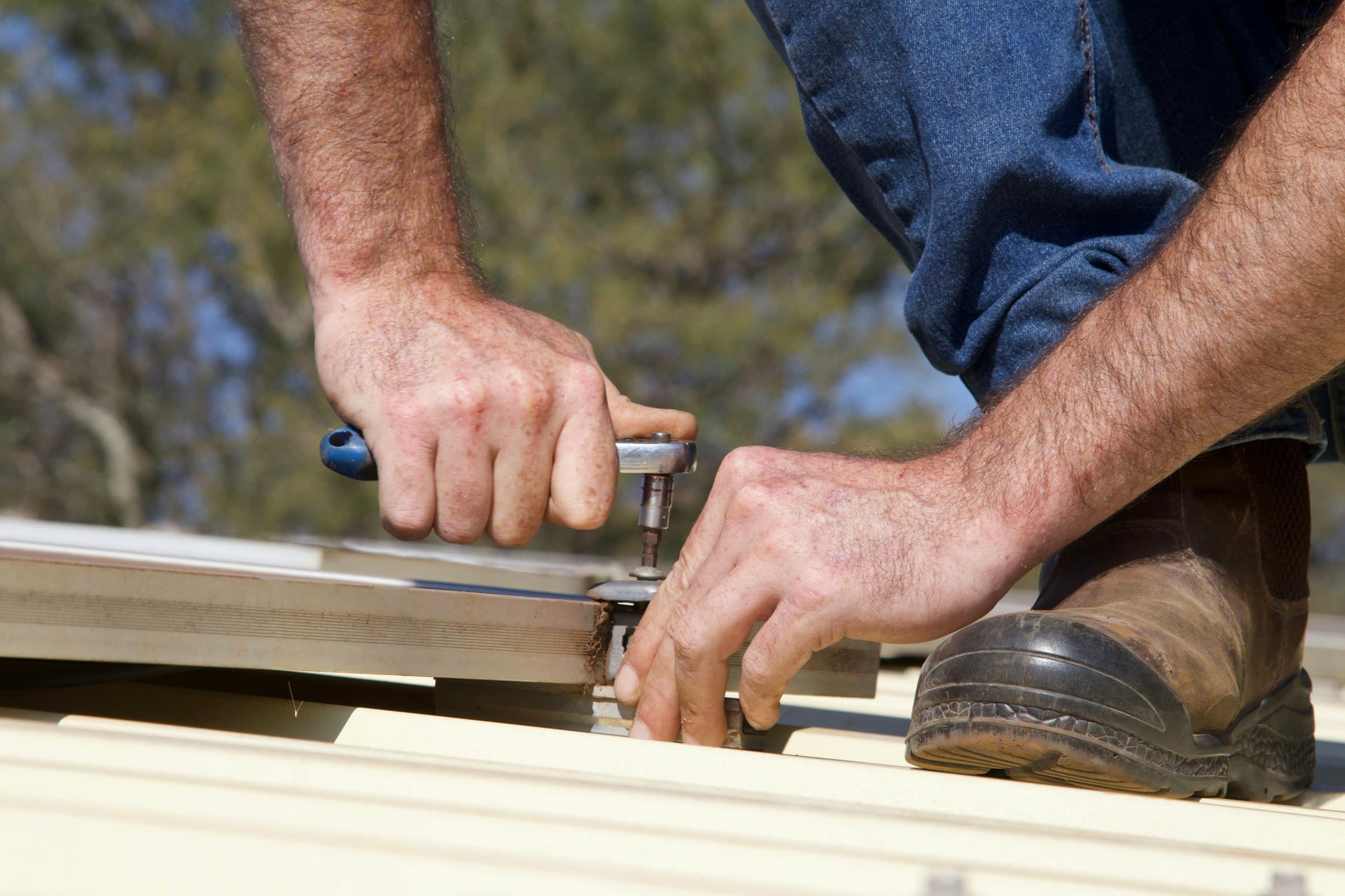 Roofer fastening shingles by hand on a Connecticut roof